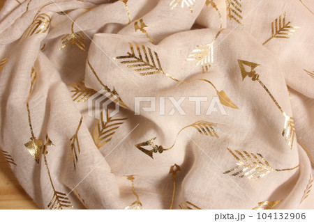Pile of Cream Colored and Gold Chiffon Fabric overhead view 104132906