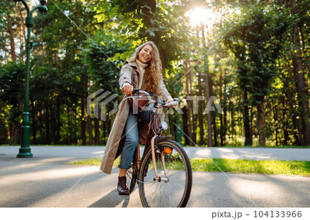 Young happy woman rides bicycle in sunny park. Beautiful woman enjoys autumn nature. Lifestyle. Young happy woman rides bicycle in sunny park. Beautiful woman enjoys autumn nature. Lifestyle. 104133966
