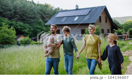 Happy family near their house with solar panels. Alternative energy, saving resources and sustainable lifestyle concept. 104136807