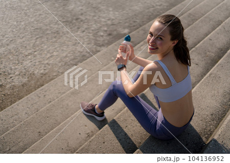 Top view of young fitness woman resting on concrete stairs after workout in city. 104136952