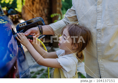 Father with his little daughter charging their electric car. 104137151