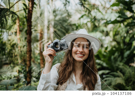 Portrait of beautiful woman photographer in botanical garden. 104137186