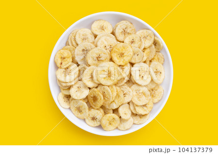 Banana slice chips on yellow background. Banana slice chips on yellow background. 104137379