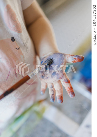 Close up of little girl painting on her own hand with tempera paint,. Close up of little girl painting on her own hand with tempera paint,. 104137502