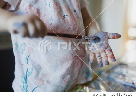Close up of little girl painting on her own hand with tempera paint,. 104137510