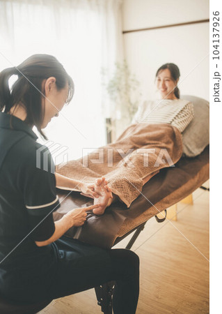 若い女性の足をマッサージする女性の整体師 若い女性の足をマッサージする女性の整体師 104137926