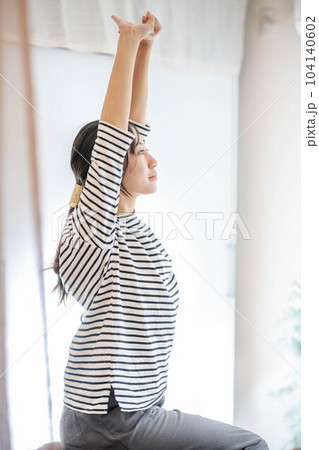 窓際でベットに座りながらストレッチをする女性 窓際でベットに座りながらストレッチをする女性 104140602