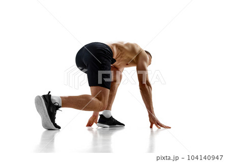 Ready, steady, go. Muscular man, professional athlete, runner standing in position to start running against white studio background 104140947