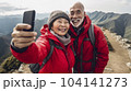 Elderly Asian couple on a hike in the mountains takes a selfie. AI content 104141273