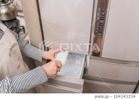 【製氷室から氷をグラスに入れる主婦】 104143334