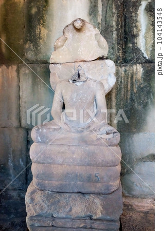 A headless sculpture of Buddha sitting in the lotus position in a Cambodian temple. 104143548