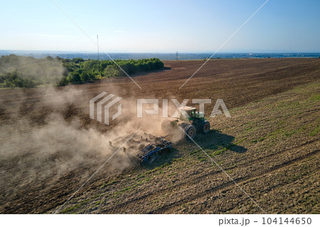 Aerial view of tractor plowing agriculural farm field preparing soil for seeding in summer 104144650