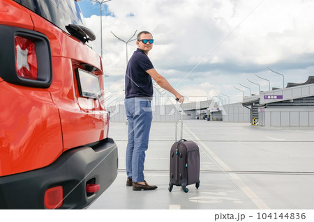 Young man with luggage in airport car park. Business trip, Travel concept 104144836