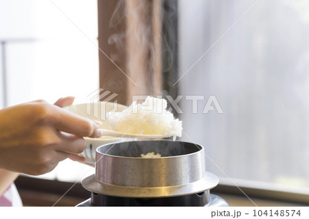 旅館朝食イメージ　お釜で炊いた炊き立てご飯をよそる女性手元 104148574