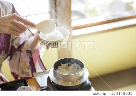 旅館朝食イメージ　お釜で炊いた炊き立てご飯をよそる女性手元 104148639