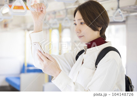 電車に乗ってスマホを見るミドル女性 104148726
