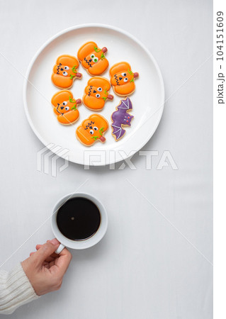 woman hand holding coffee cup during eating funny Halloween Cookies. Happy Halloween day, Trick or Threat, Hello October, fall autumn, Traditional, party and holiday concept woman hand holding coffee cup during eating funny Halloween Cookies. Happy Halloween day, Trick or Threat, Hello October, fall autumn, Traditional, party and holiday concept 104151609