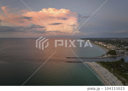 Aerial view of Nokomis beach and South and North Jetty in Sarasota County, USA. Many people enjoing vacation time swimming in gulf water and relaxing on warm Florida sun at sunset 104153023