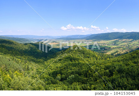 Aerial view of mountain hills covered with dense green lush woods on bright summer day. Aerial view of mountain hills covered with dense green lush woods on bright summer day. 104153045