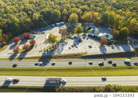 Aerial view of big rest area near busy american freeway with fast moving cars and trucks. Recreational place during interstate travel concept Aerial view of big rest area near busy american freeway with fast moving cars and trucks. Recreational place during interstate travel concept 104153393