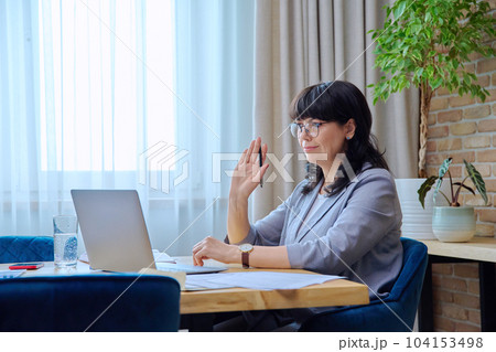 Mature business woman at workplace using laptop for virtual video meeting Mature business woman at workplace using laptop for virtual video meeting 104153498