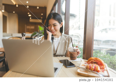 Happy smile asian woman eating bread at cafe sitting near window indoors on day 104154101
