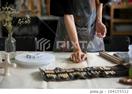 Close-up image of a male artist potter kneading raw clay at his worktable in his pottery studio. 104155512