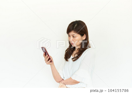 スマートフォンを見て険しい表情の女性 スマートフォンを見て険しい表情の女性 104155786