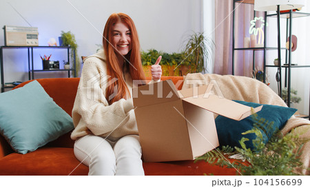 Happy young woman shopper unpacking cardboard box delivery parcel online shopping purchase at home 104156699