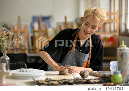 A happy young Asian gay man enjoys making handcrafted earthenware A happy young Asian gay man enjoys making handcrafted earthenware 104157054