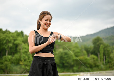 A happy Asian woman is checking her calories burned on her smartwatch after jogging A happy Asian woman is checking her calories burned on her smartwatch after jogging 104157506