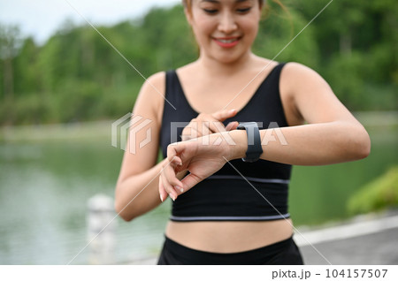Close-up image of a sporty Asian woman checking her calories burned on her smartwatch Close-up image of a sporty Asian woman checking her calories burned on her smartwatch 104157507