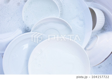 Dishes and bowls in water and bubbles of dishwashing liquid Dishes and bowls in water and bubbles of dishwashing liquid 104157722