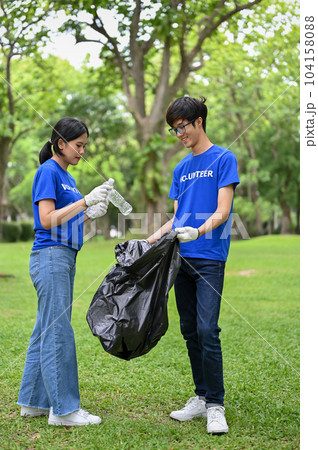 Happy Asian female and male volunteers collect trash and plastic bottles into a garbage bag Happy Asian female and male volunteers collect trash and plastic bottles into a garbage bag 104158088