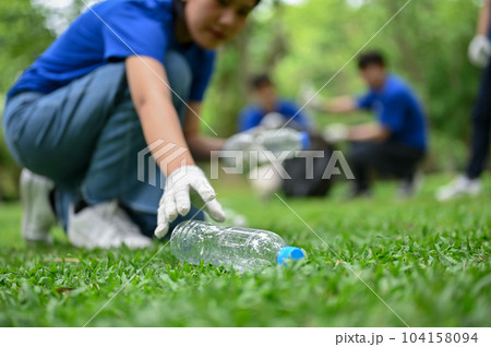 A beautiful Asian female volunteer collecting trash and a plastic bottle in the public park A beautiful Asian female volunteer collecting trash and a plastic bottle in the public park 104158094