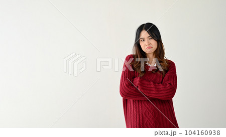 Pretty Asian woman stands against an isolated white background with her arms crossed. who cares Pretty Asian woman stands against an isolated white background with her arms crossed. who cares 104160938