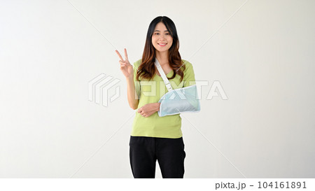 A happy woman with her accidentally broken arm in an arm sling is showing her fingers 104161891