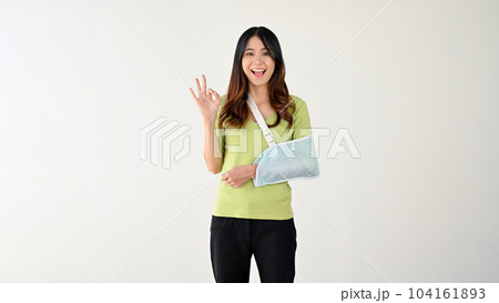 A happy woman with her broken arm in an arm sling is showing the Okay hand sign A happy woman with her broken arm in an arm sling is showing the Okay hand sign 104161893