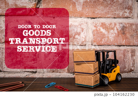 Door to Door Goods Transport Service. Miniature forklift on a wooden table Door to Door Goods Transport Service. Miniature forklift on a wooden table 104162230