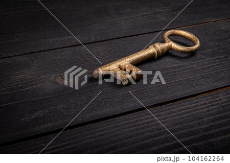 Concept of success. Gilded antique key on dark wood texture background. Close up Concept of success. Gilded antique key on dark wood texture background. Close up 104162264