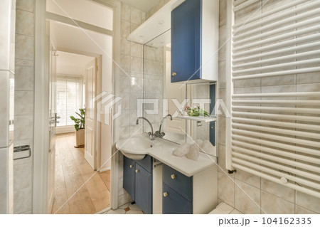 a small bathroom with blue cabinets and white tiles on the walls, along with a wooden door leading to another room 104162335