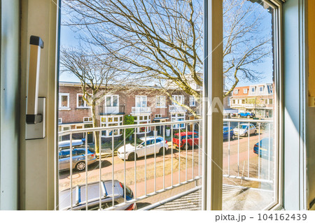 an outside area with cars parked in the lot and trees on the other side of the street as seen through a window an outside area with cars parked in the lot and trees on the other side of the street as seen through a window 104162439