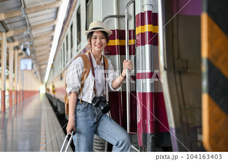 A beautiful Asian female traveler backpacker is boarding the train at the railway station. 104163403
