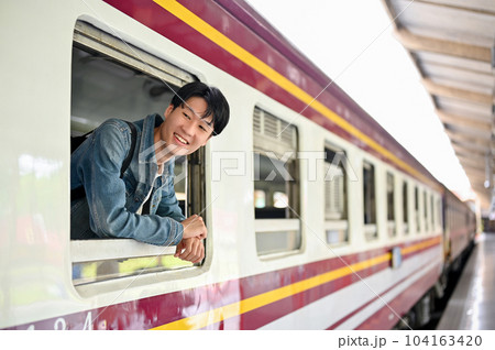 An Asian male backpacker is taking his head out of the train window An Asian male backpacker is taking his head out of the train window 104163420