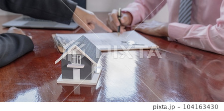 home model. The real estate agent explains the business contract 104163430
