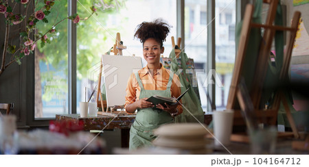 Beautiful american african artist woman painting in art studio at the university classroom 104164712
