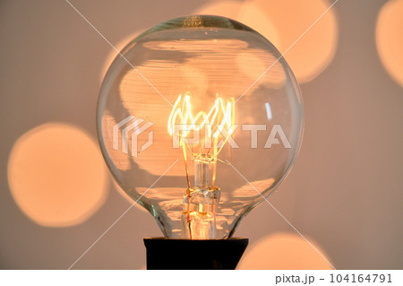 Incandescent light bulb with christmas round bokeh. 104164791