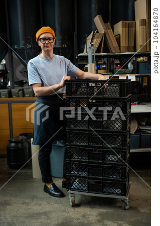 Roasting plant worker uploads coffee beans packs in boxes. 104164870
