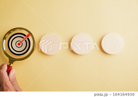 A magnifier glass magnifying a target board, emphasizing importance of hitting business objectives. Against with copy space, it symbolizes the pursuit of innovation and charting a winning path. A magnifier glass magnifying a target board, emphasizing importance of hitting business objectives. Against with copy space, it symbolizes the pursuit of innovation and charting a winning path. 104164930