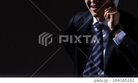 黒背景で詐欺電話をかける男性ビジネスマン 104165202